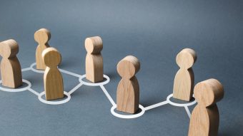 Wooden blocks representing people with while lines connecting them.