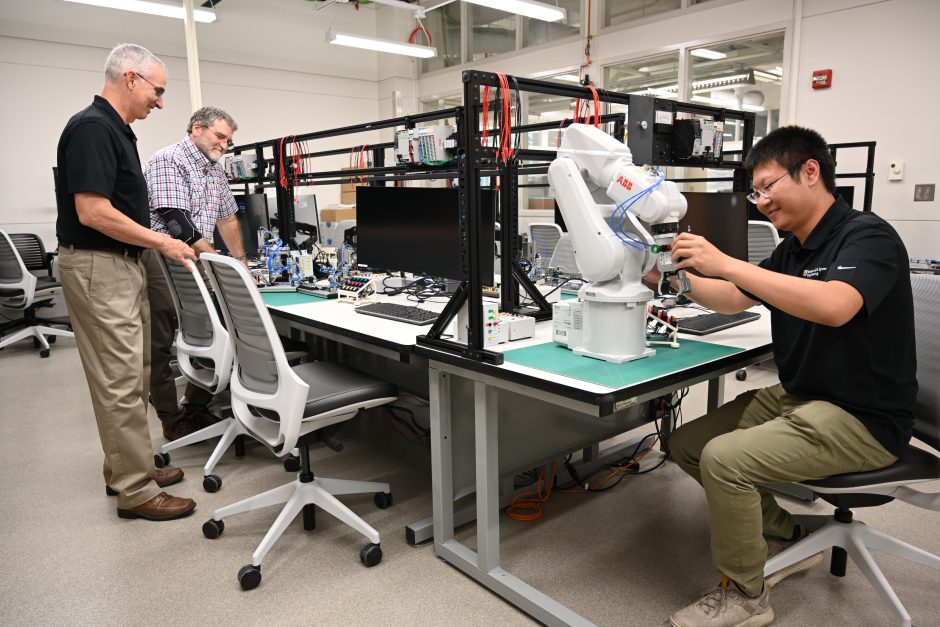 three researchers in a lab looking at equipment on a lab table