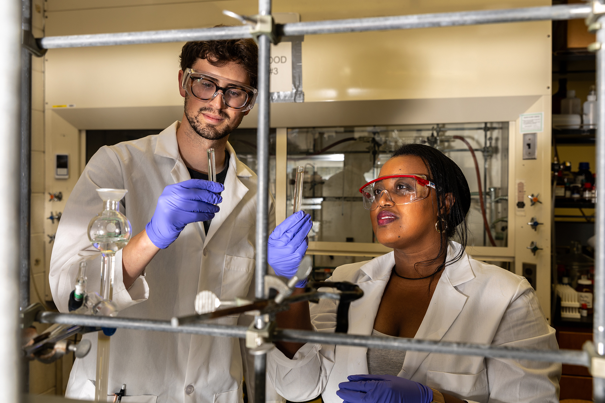Doctoral student Faith Aynekulu helping undergraduate chemistry student Ben Shostak in a chemistry building lab