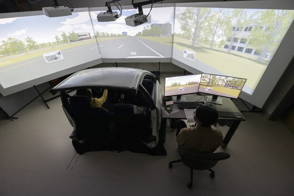 Picture of a car in a transportation simulation lab surrounded by 180 degrees of computer screens