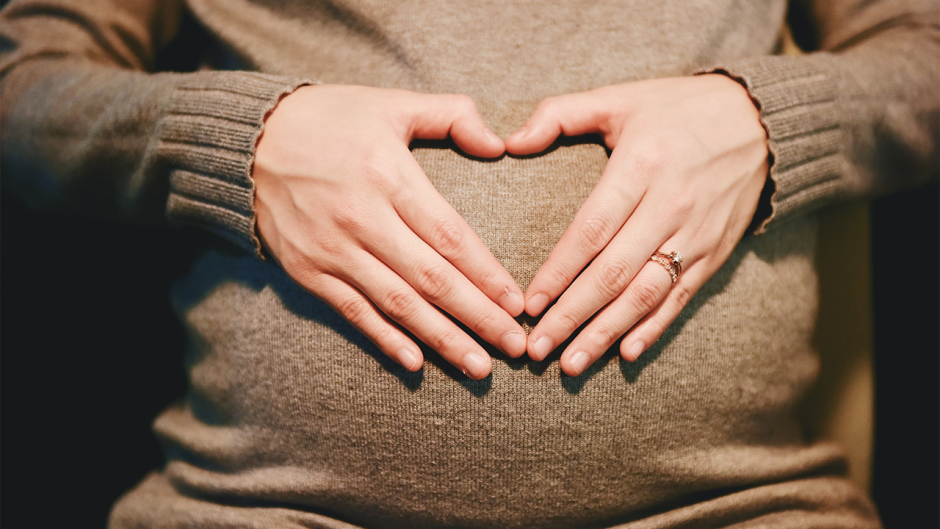 pregnant women putting her hands into a heart