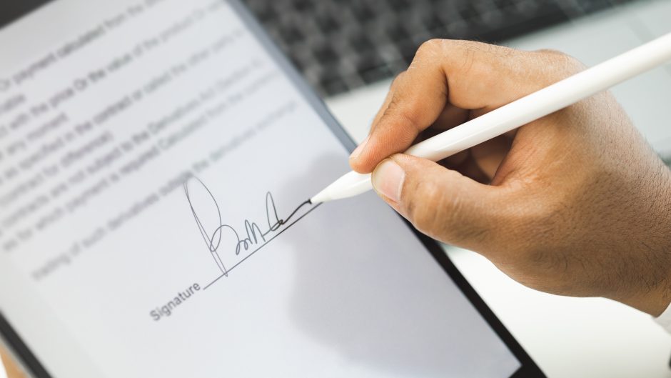 Hand pictured with pen writing a signature