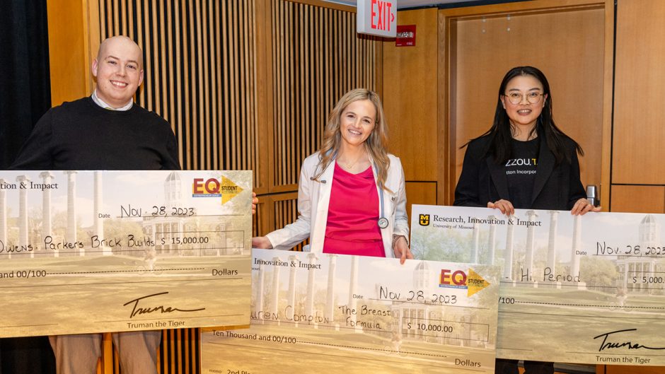 three winners holding big checks