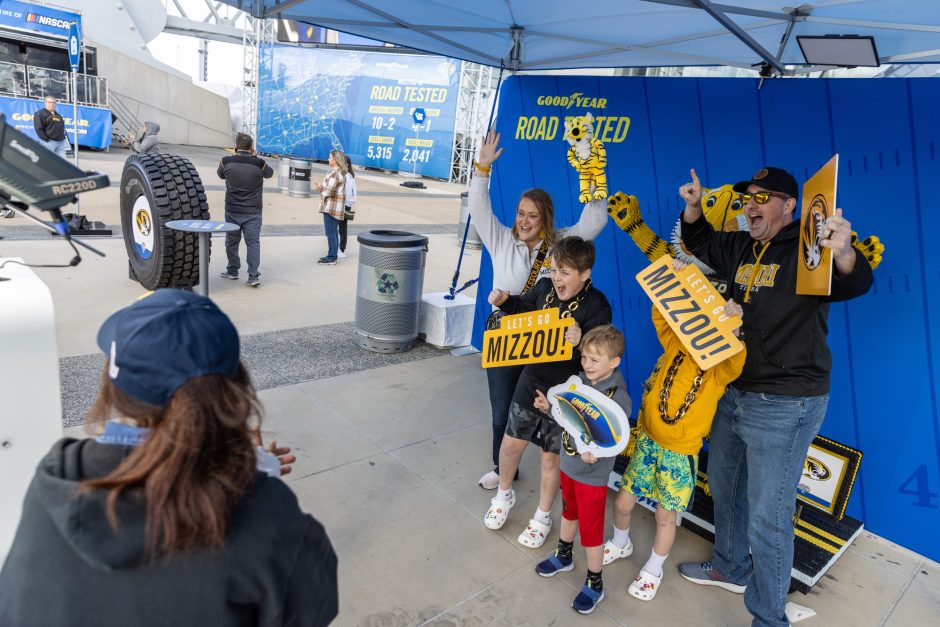 A family of four poses with Mizzou signs at the Battle of the Bands at AT&T Stadium in anticipation of the Cotton Bowl between Mizzou and Ohio State.  
