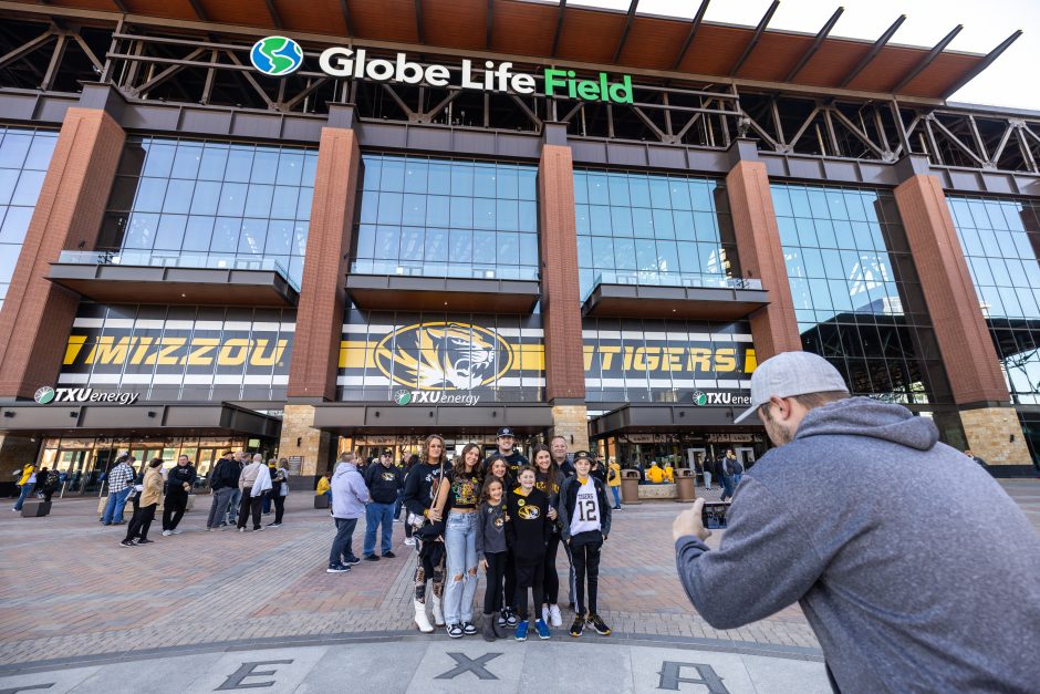 A family poses in front of Mizzou Tigers signage outside of Globe Life Field