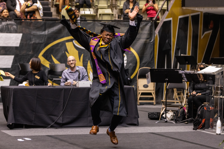 a graduate dancing while on his way to grab his diploma