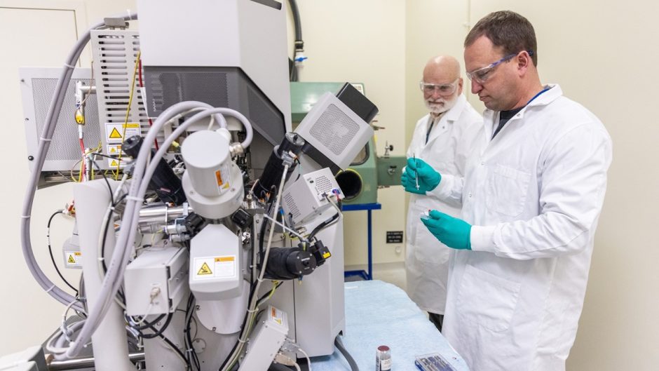 two scientists working with an electron microscope in a scientific lab