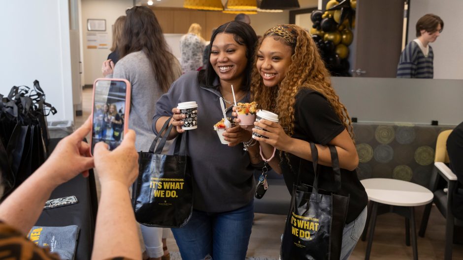 two women eat snacks and take a photo at the grand opening