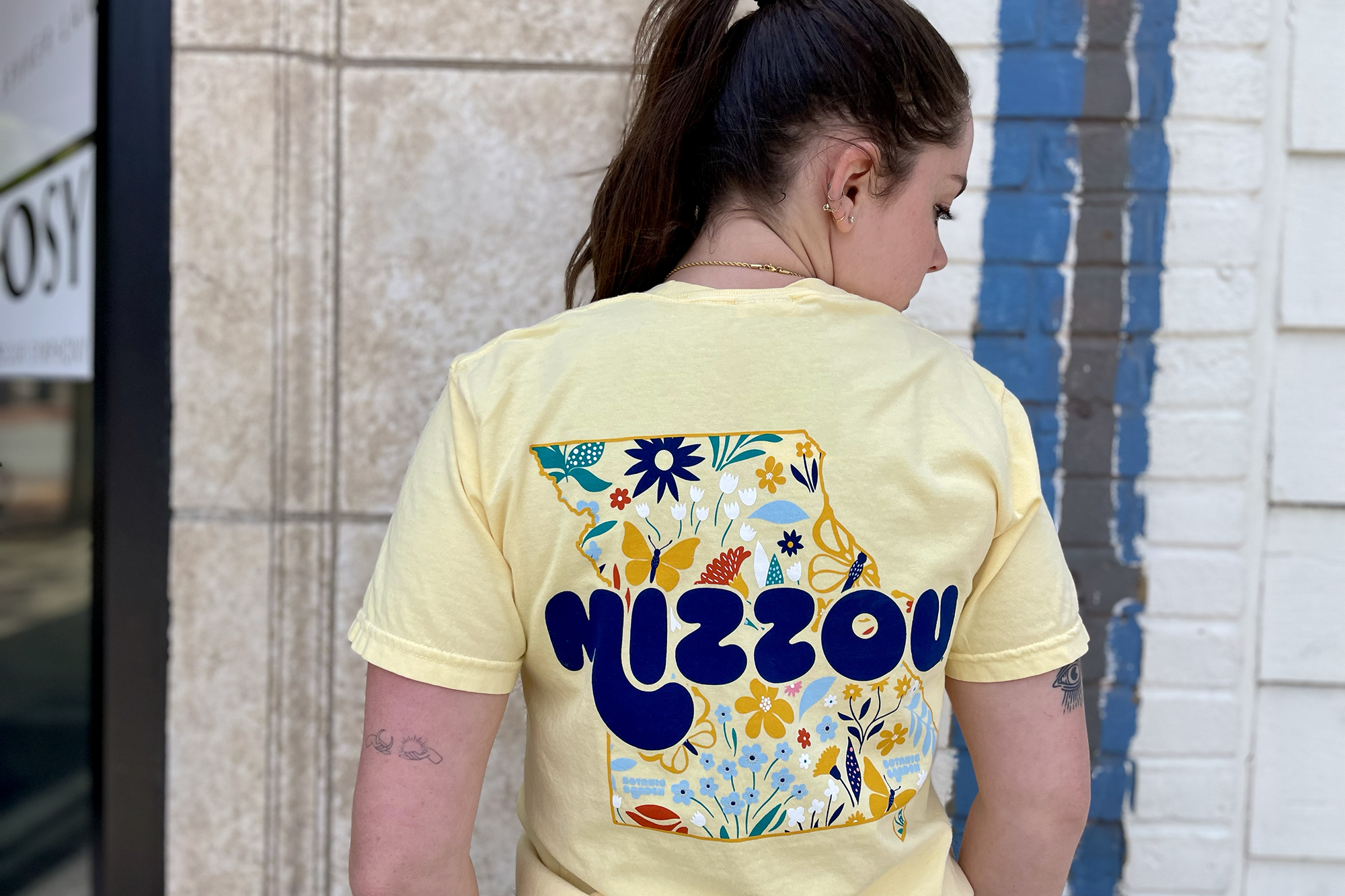 a girl in a yellow botanic garden shirt that says mizzou