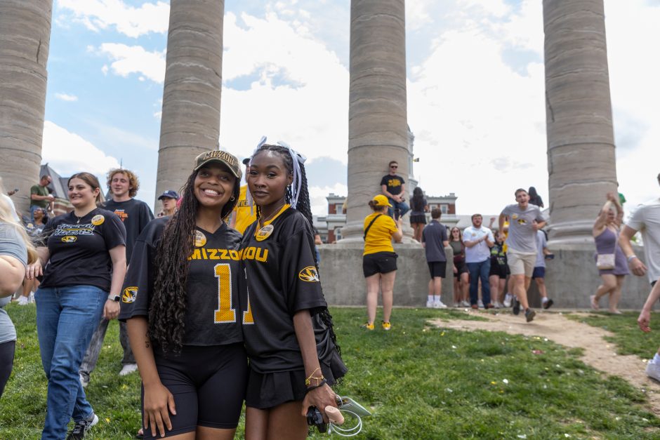 Two students in Mizzou clothing smile for camera