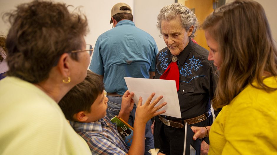 Temple Grandin looks at a student's portfolio