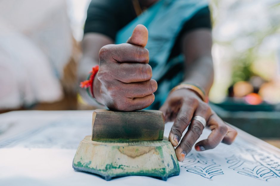 Hands imprinting design onto fabric.