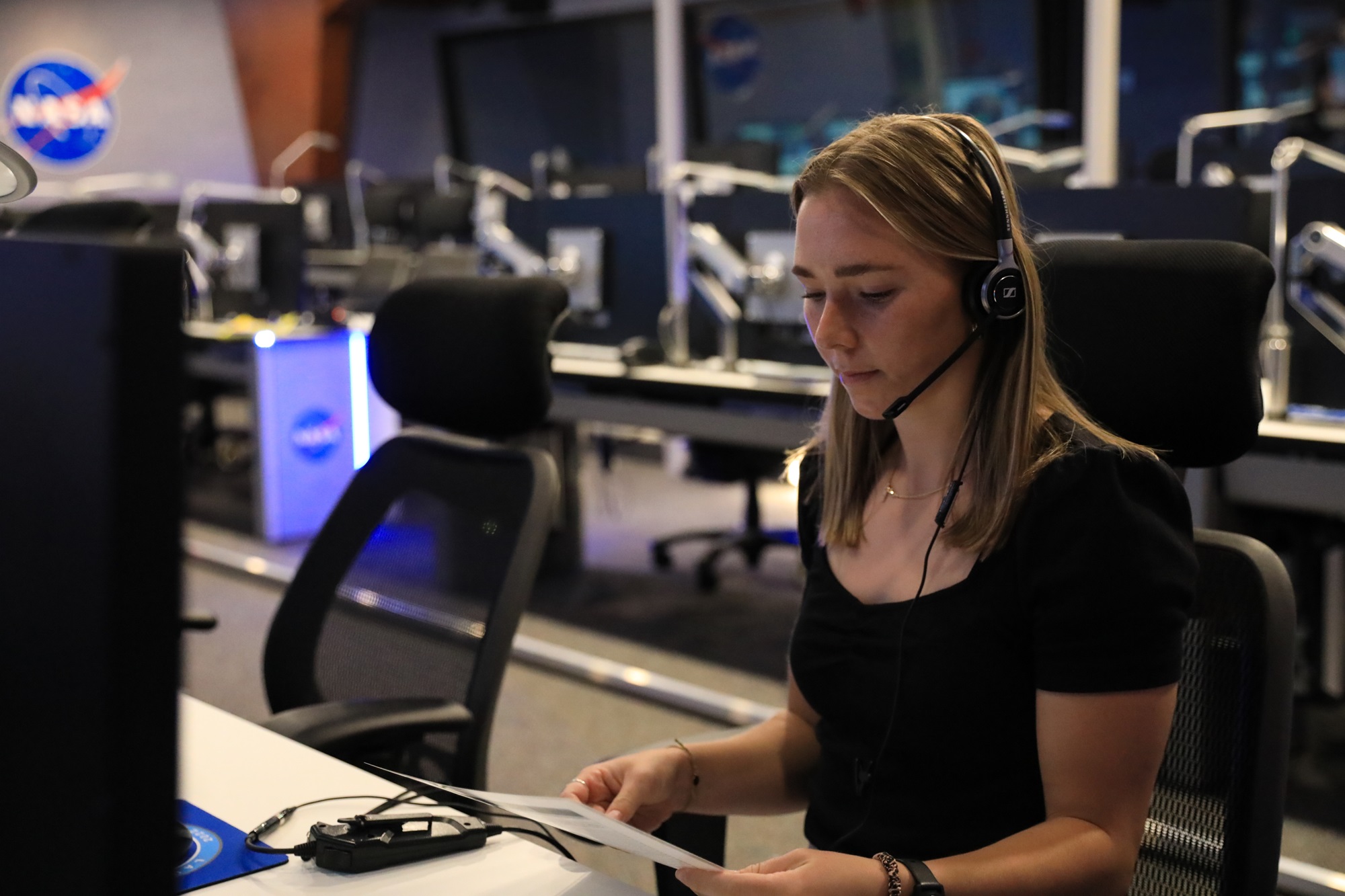 a person looking at a sheet of paper in front of a computer with a pair of headphones on