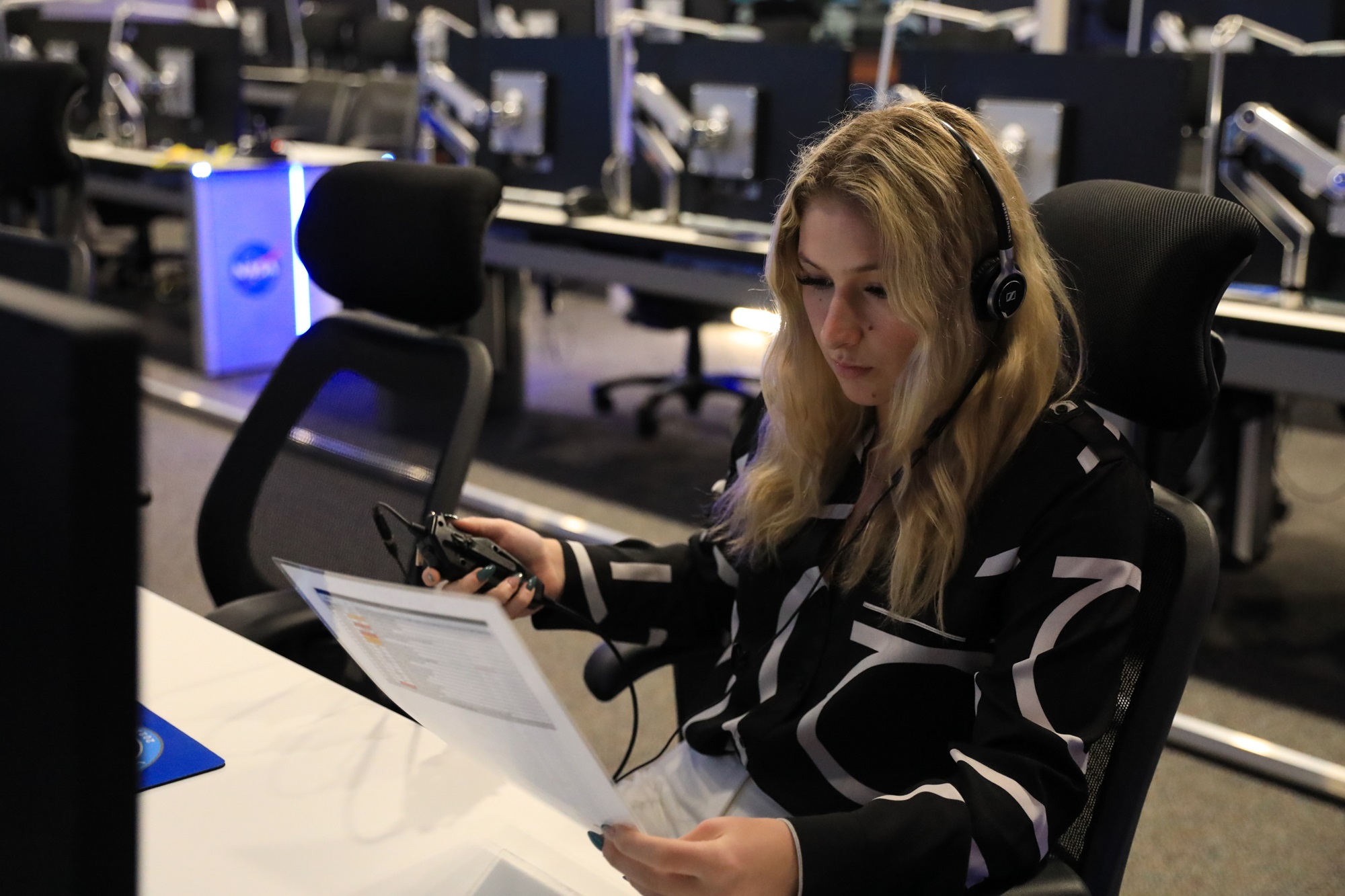 a person looking at a sheet of paper in front of a computer with a pair of headphones on