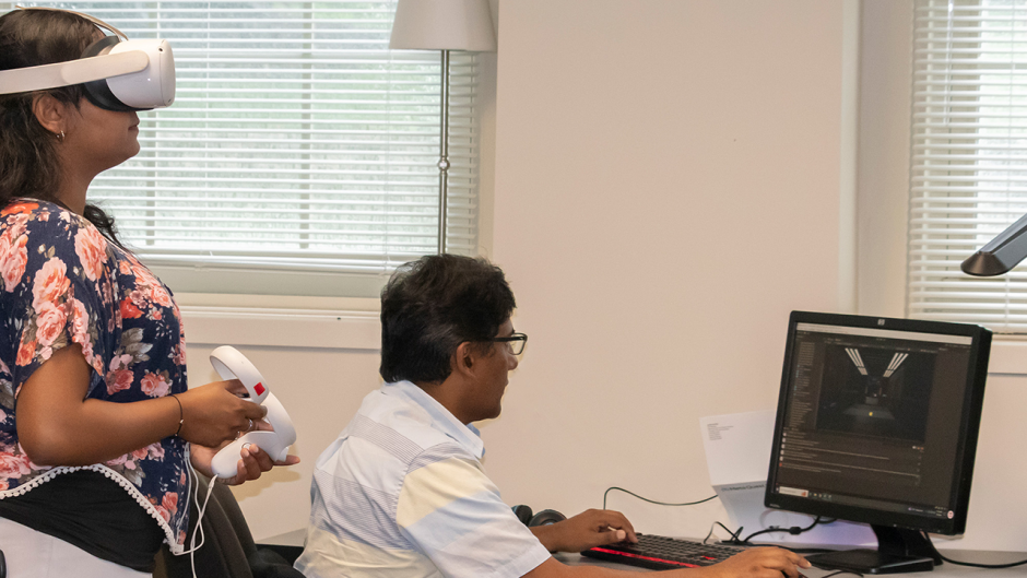 Two people with VR equipment at computer