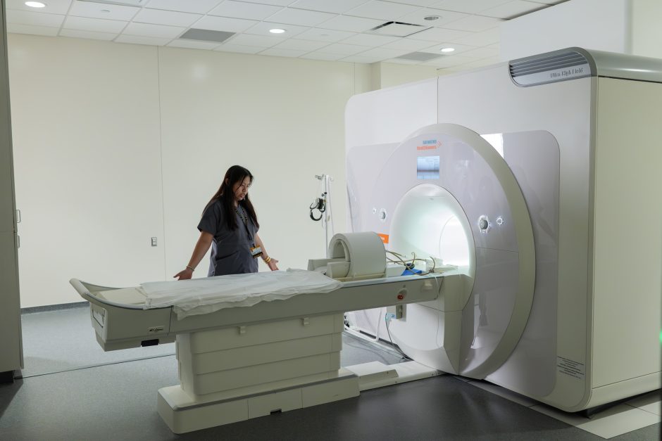 Person stands over MRI machine