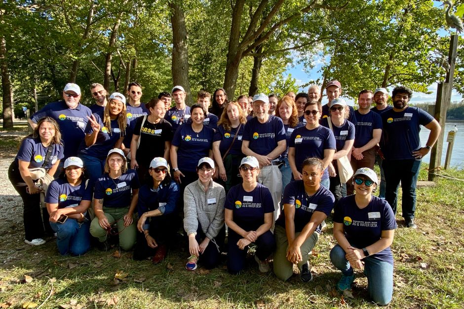 Group of people pose for photo in front of trees and river