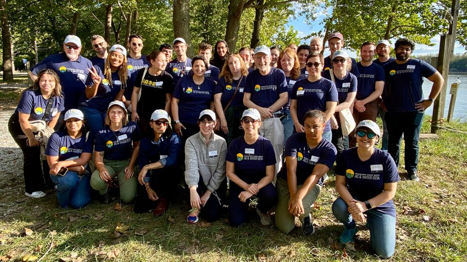 Group of people pose for photo in front of trees and river