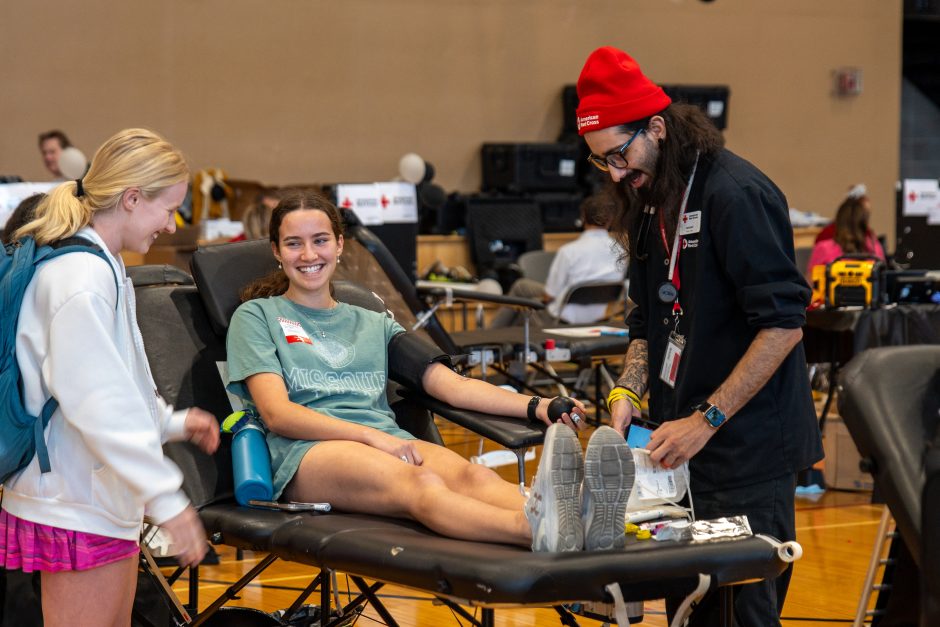 Student smiles at camera as she gives blood