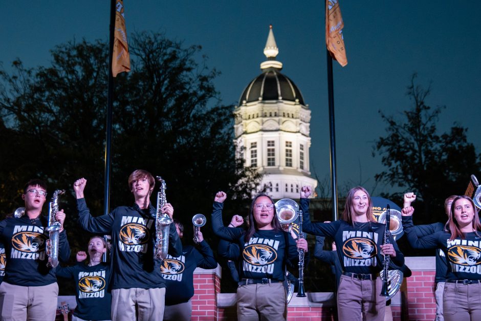 Students in black with instruments in front of white dome