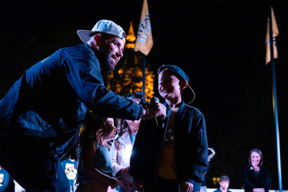 Man holds microphone to child during spirit rally