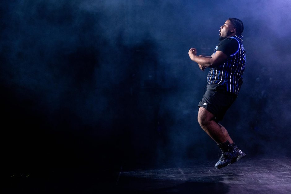 Student performs at step show in front of blue smoke