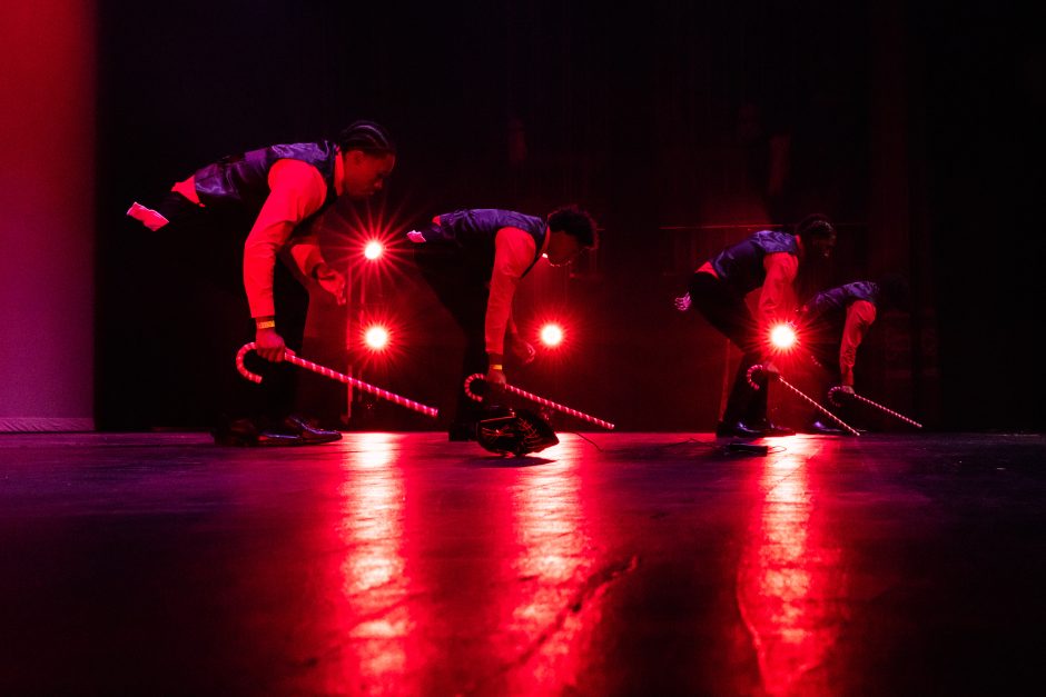 Students perform with canes in front of red lights