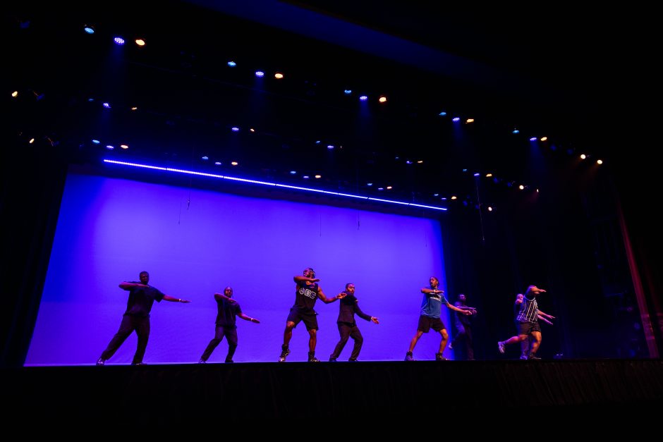 Students perform in front of purple light