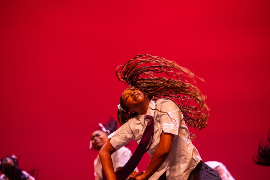 Students perform in front of red screen