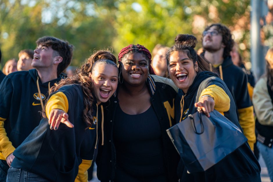 Students smile at camera during parade