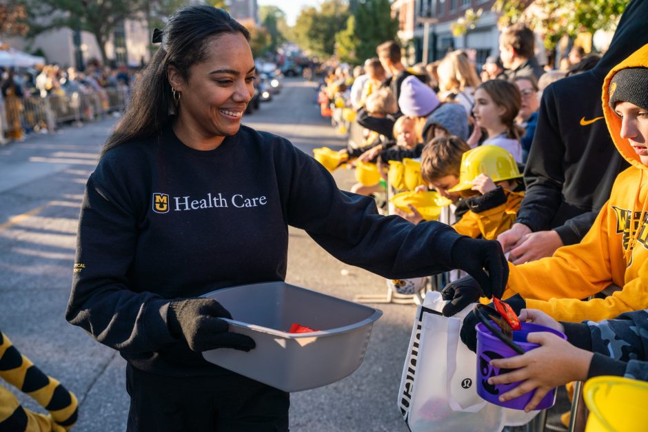 Woman wearing MU Health Care shirt passes out candy at parade