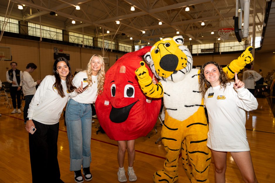 Truman and blood mascots with three students smile at camera