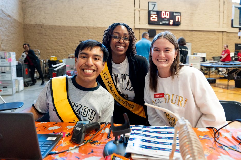 Three students at blood drive smile at camera