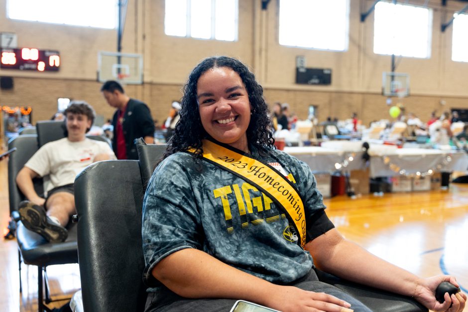 Student smiles at camera as she gives blood