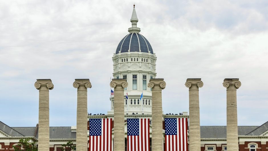 Columns at University of Missouri with American flags between them and Jesse Hall in the background