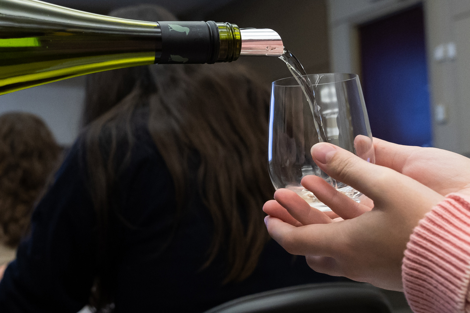 Hand holding glass while wine is being poured