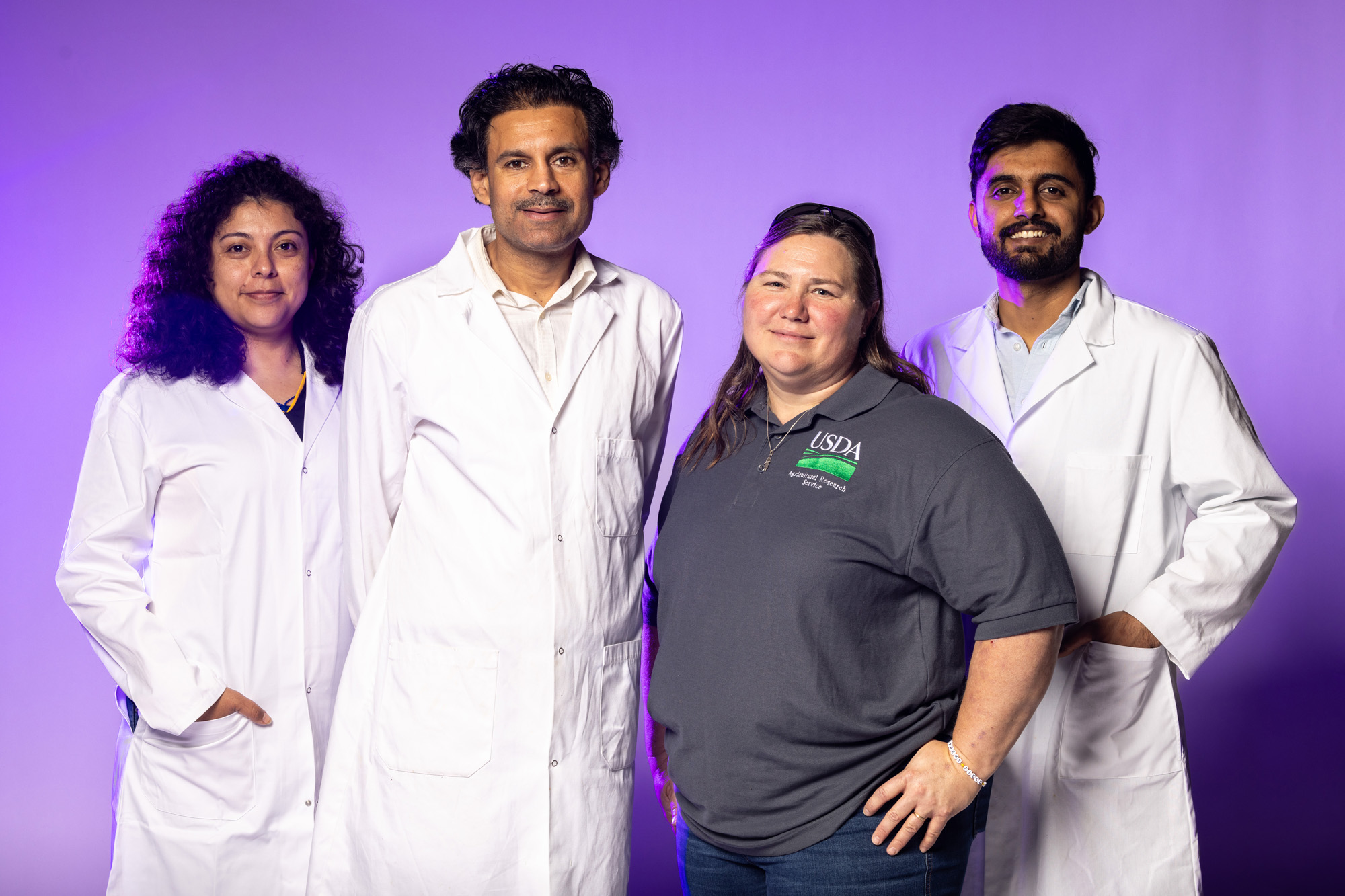 People in lab coats in front of purple screen