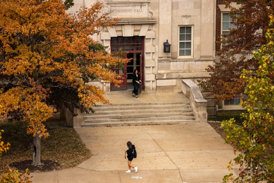 A student walks in front of white building