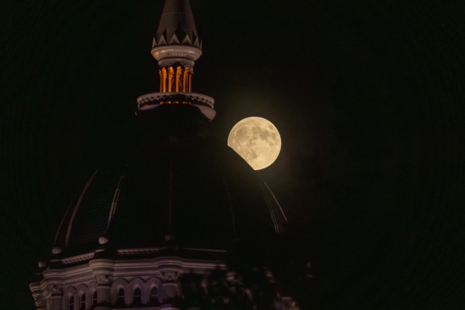 A harvest moon peeks over a campus building