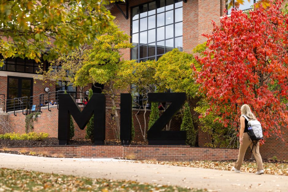 A student walks in front of the M-I-Z statue