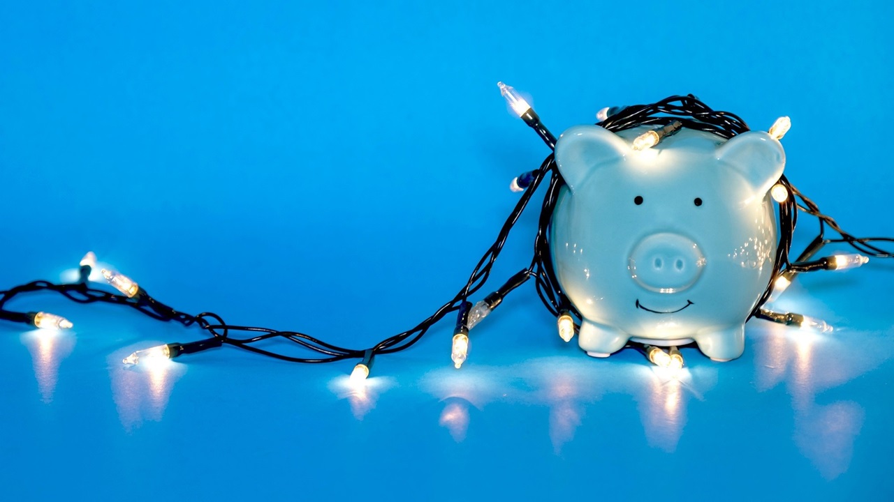 Piggy bank wrapped in a string of white lights with a blue background