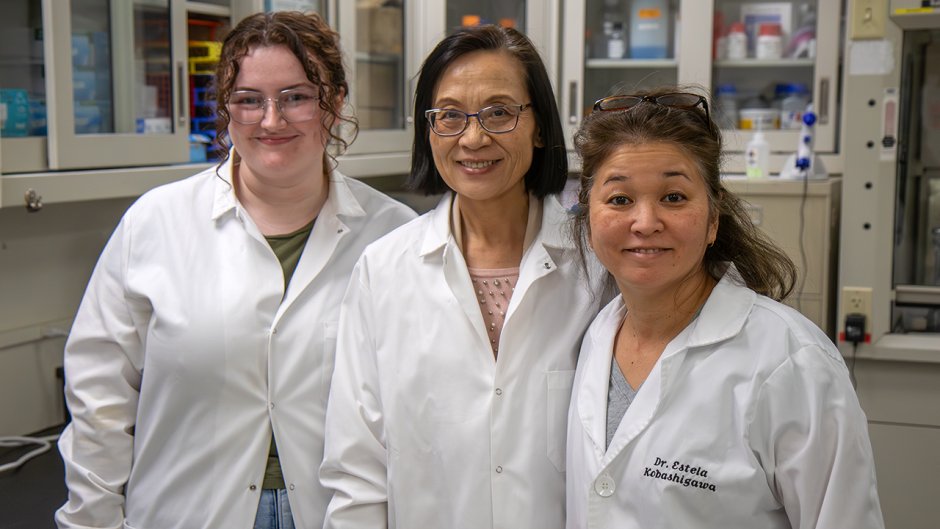 Three scientists in white coats in lab