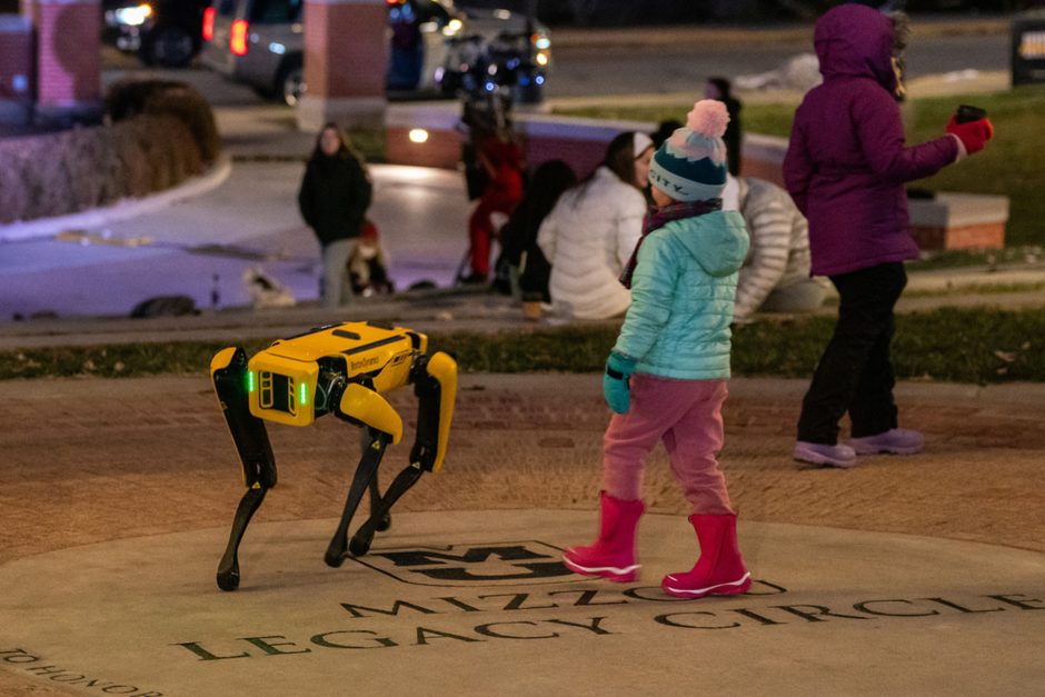 Child looks at robotic dog