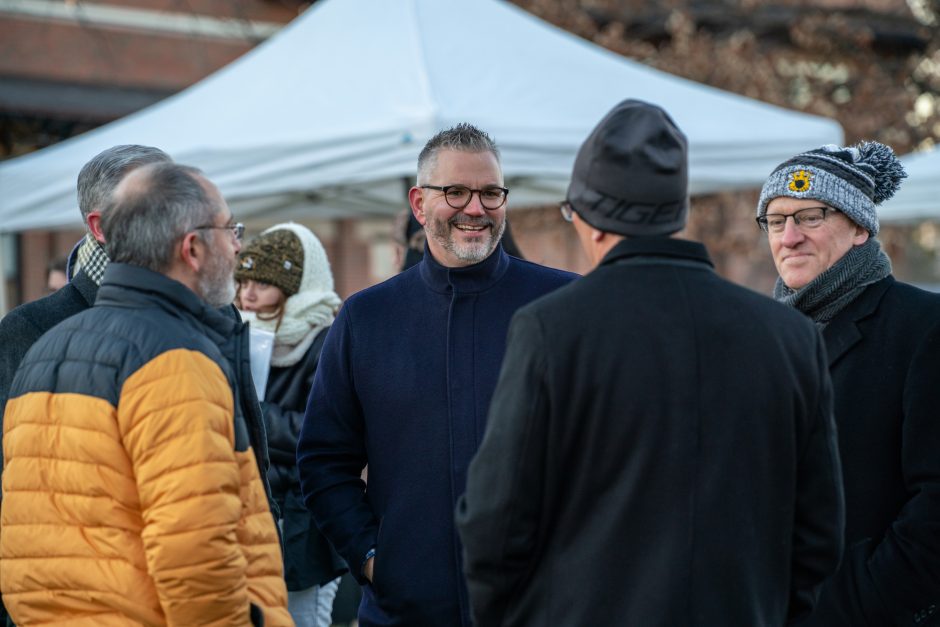 Three people in coats talk outside