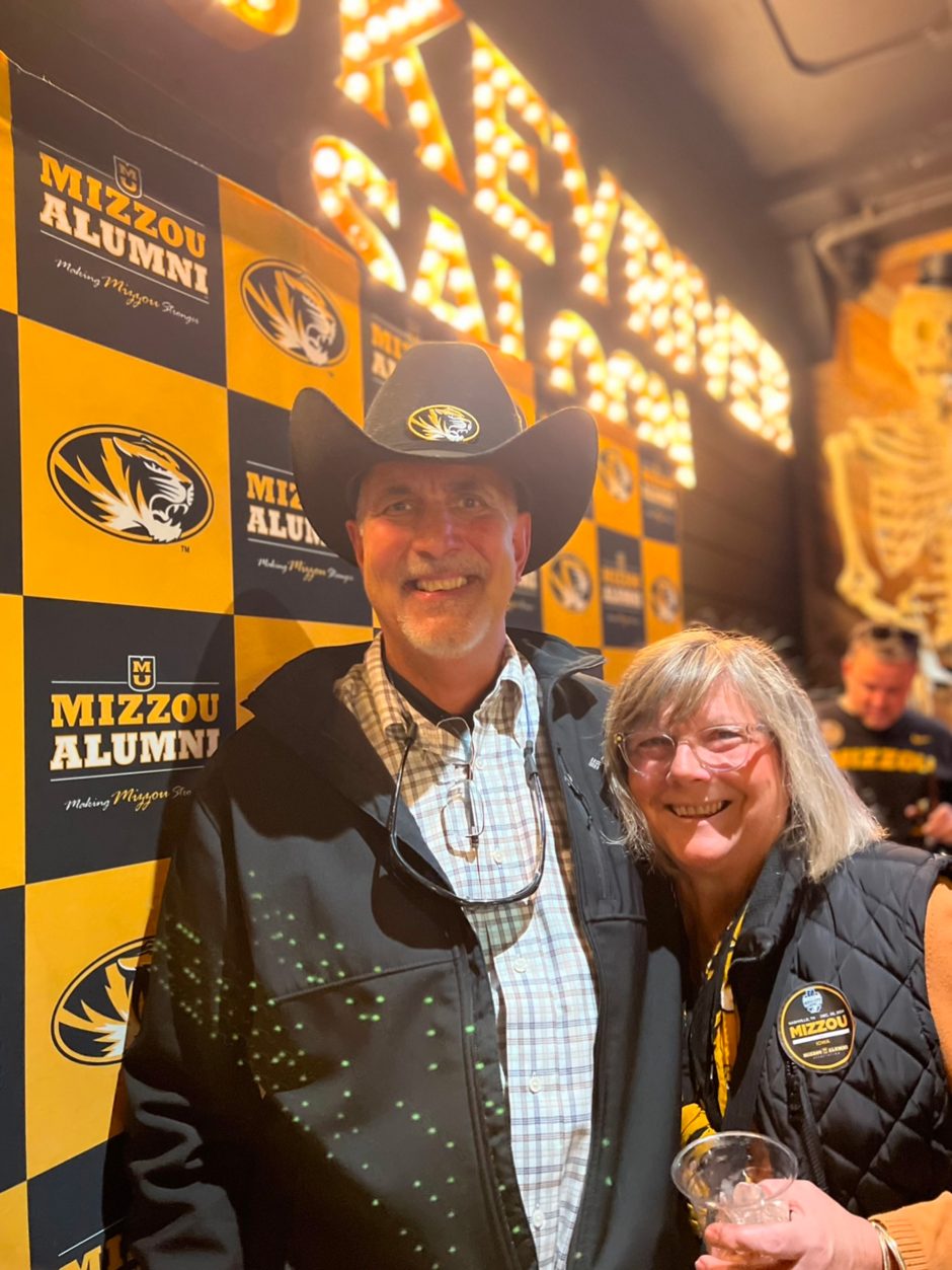 Two people in front of Mizzou background