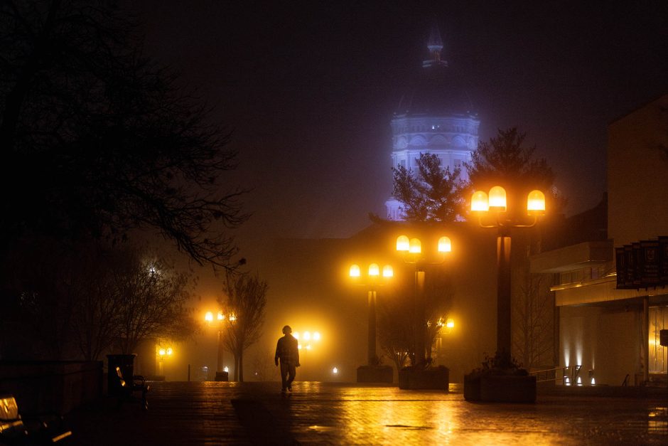 Person walking on campus illuminated by lights and fog