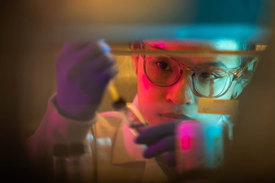 Person with goggles working in lab illuminated with pink and blue lights