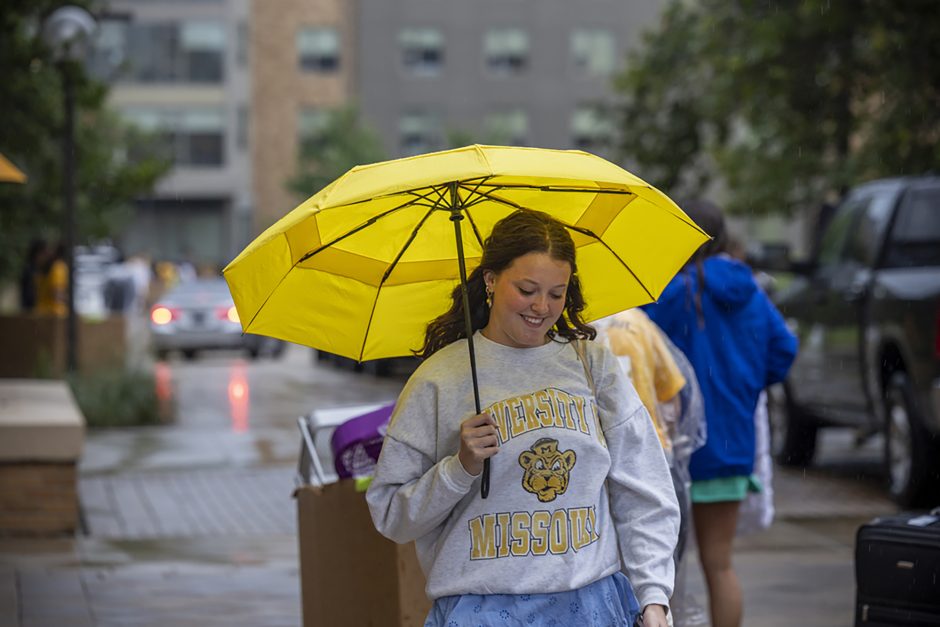 Person carrying yellow umbrella on campus