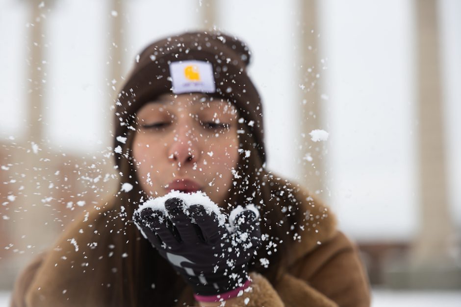 Person blows snow from gloved hand