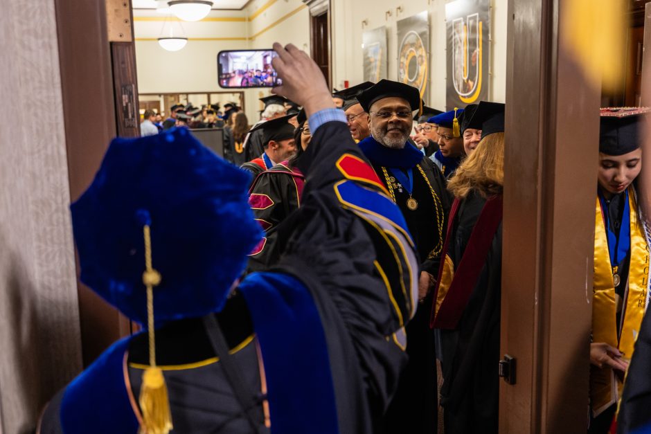 A person takes a photo of faculty in line